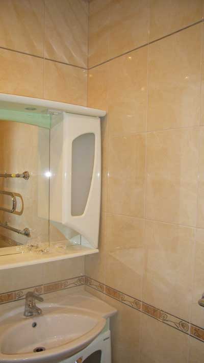 Отделка ванной комнаты: плиточное покрытие стен, зеркало и раковина
